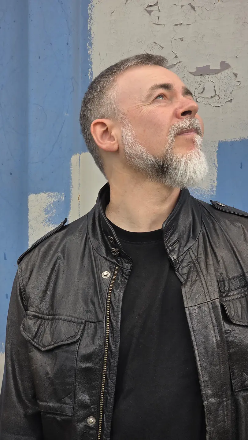 Portrait von Roman Scherer vor einer blau-grauen Wand